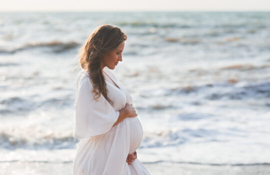 trudnica na plaži drži svoj trbuh