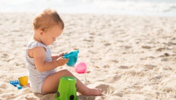 mala beba se igra na plaži s kanticama