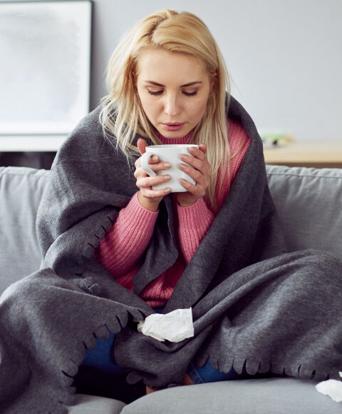 Prehlađena žena pije čaj.