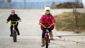 Dvoje djeteta voze bicikl zimi.