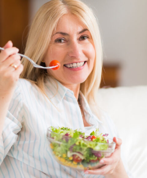 Nasmiješena žena jede salatu.