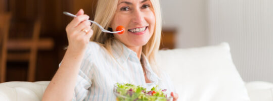 Nasmiješena žena jede salatu.
